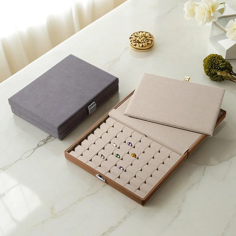 Beige and grey lockable jewelry storage box open, with ring rolls and a compartment tray