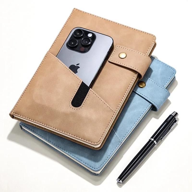 Tan PU leather A5 notebook planner with a phone pocket, on a desk with a pen